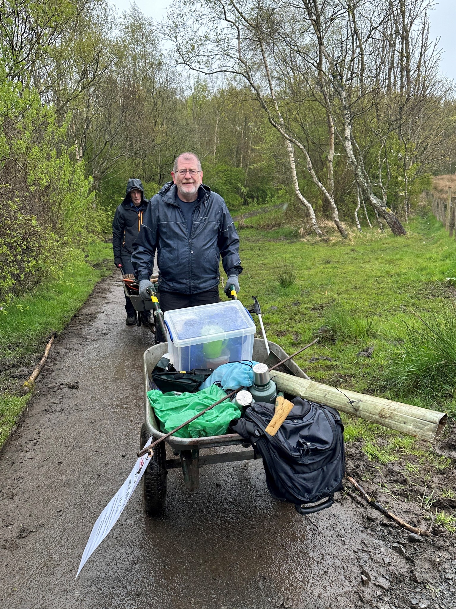 Path volunteer with gardening maintenance tools and wheelbarrow