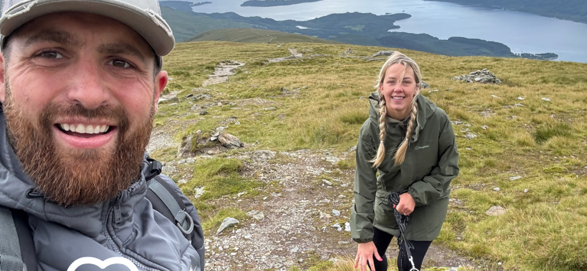 Man woman and dog at top of mountain with donate icon