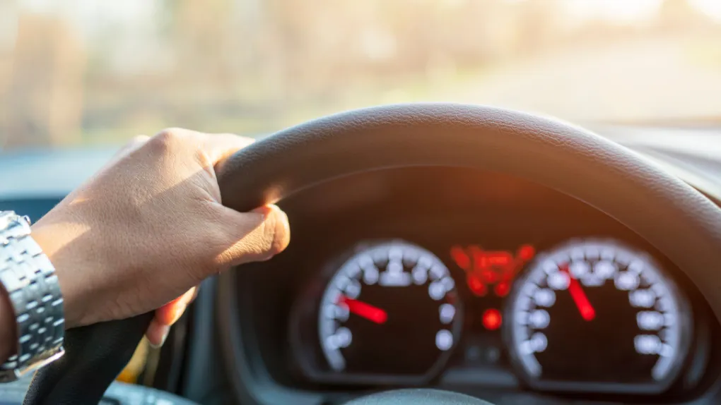 Person driving car with fuel and speedometer gauge in background