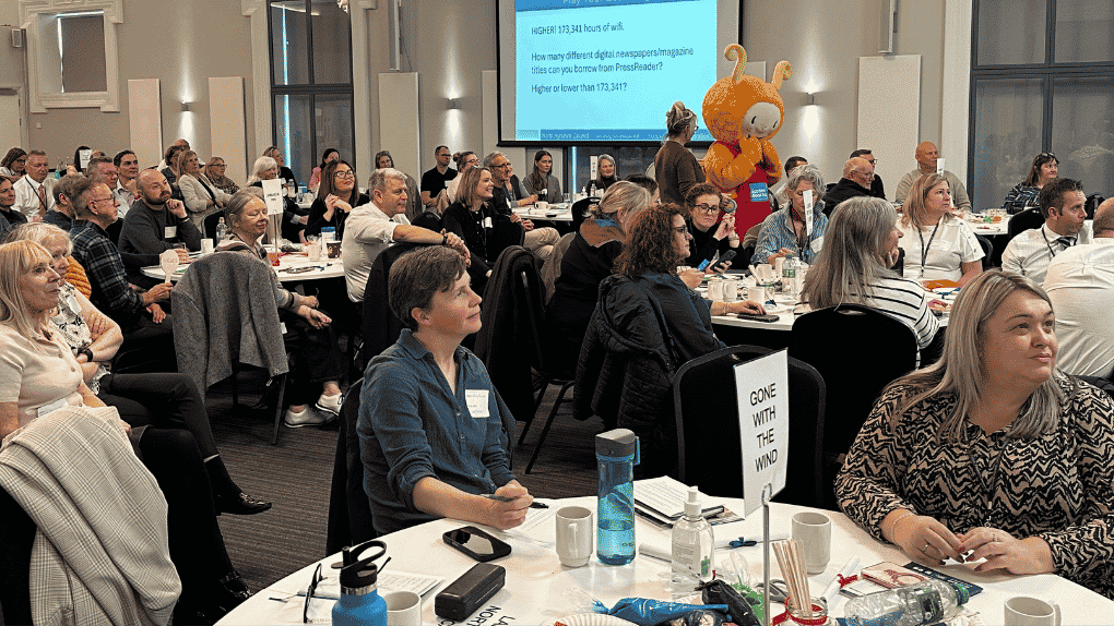 A general view of a large room of people sitting at tables