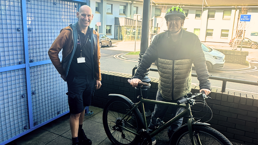 Member of Travel Smart team with colleague loaning bike outside Marress House