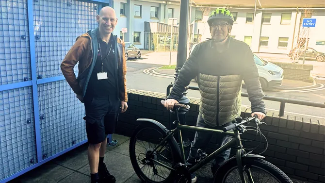 Member of Travel Smart team with colleague loaning bike outside Marress House