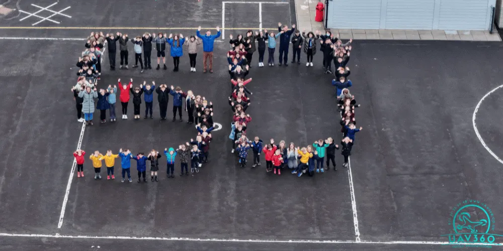 People creating the number fifty in a school playground with their bodies