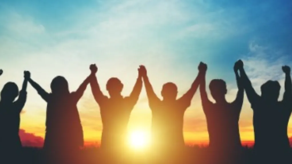 Silhouette of group with hands up and sun going down