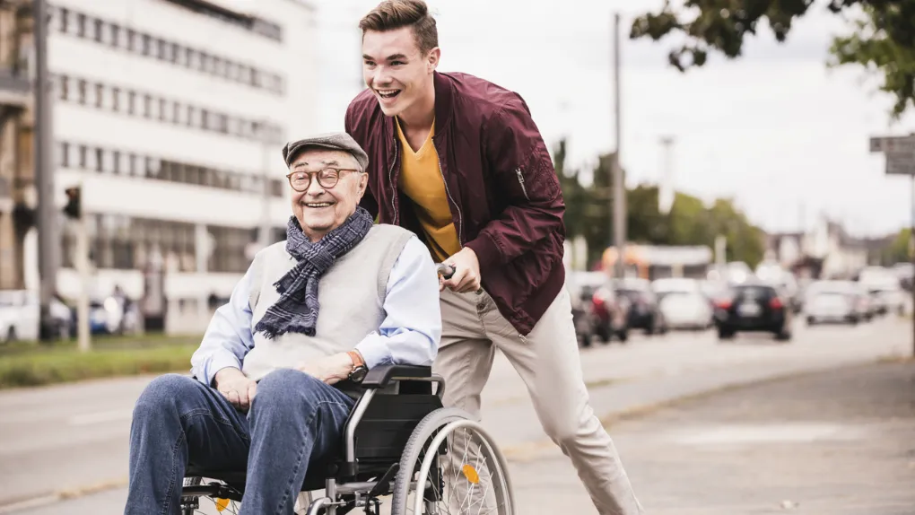 Boy pushing man in wheelchair smiling